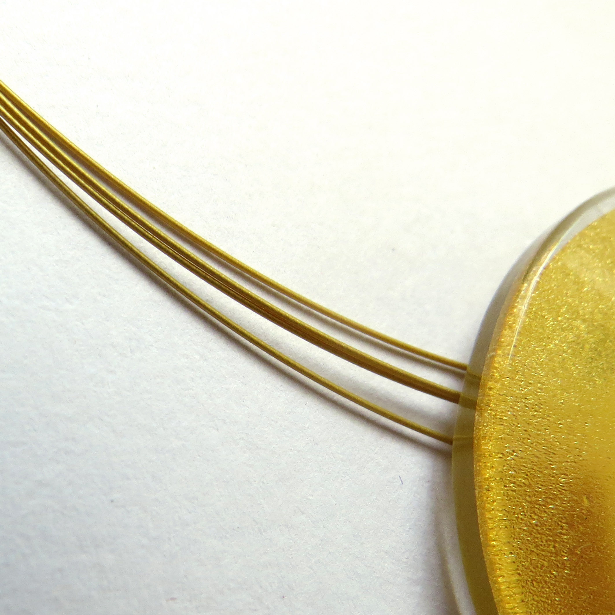 Detailed view of the gold wires with a sun pendant.